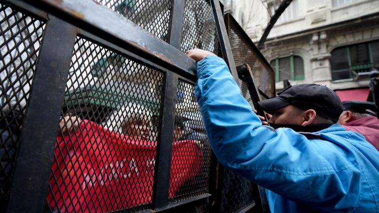 Demonstrators are kept behind a barrier as they protest outside...