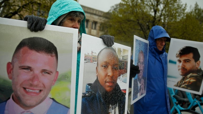 Protesters hold photographs of victims, including Melvin Riffel, left, of...