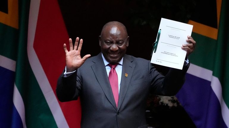 South African President Cyril Ramaphosa shows the signed bill for...