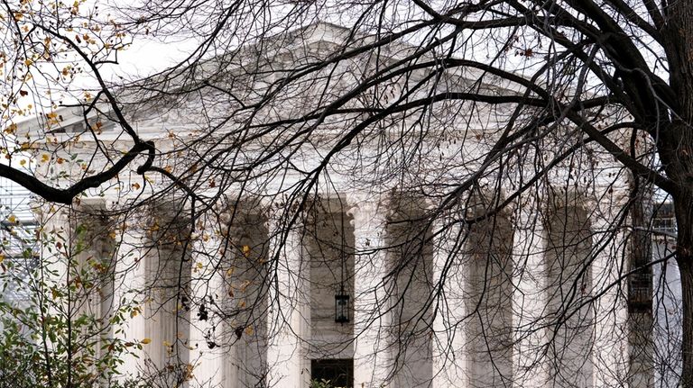 The Supreme Court is seen amid bare tree branches, on...