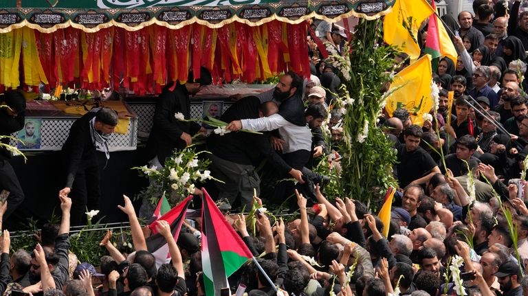 Iranians follow the truck carrying the coffins of Hamas leader...