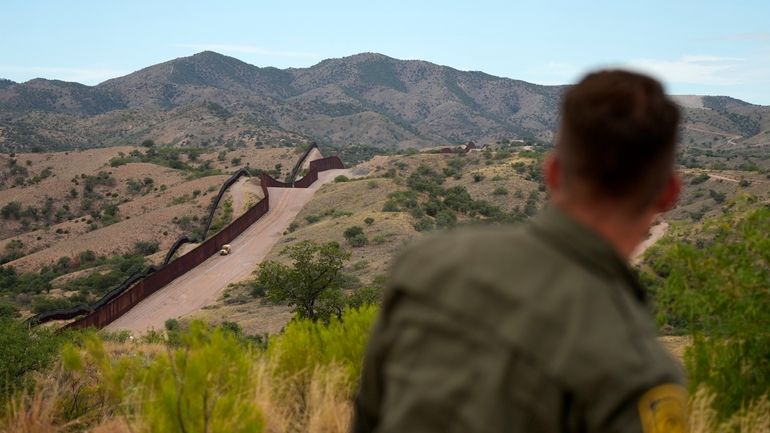 Border patrol agent Pete Bidegain looks from a hilltop on...