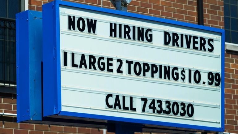 A hiring sign is displayed at a restaurant in Chicago,...