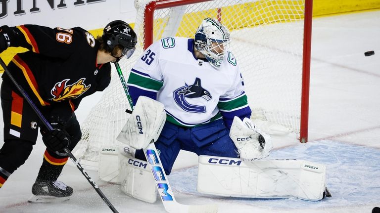 Vancouver Canucks goalie Thatcher Demko, right, blocks the net as...