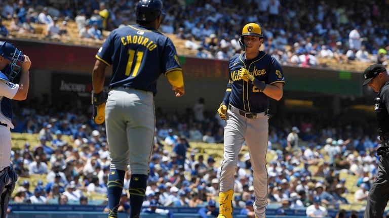 Milwaukee Brewers' Jackson Chourio, left, waits to congratulate Christian Yelich...