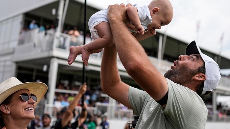 Scottie Scheffler holds his son Bennett Ezra Scheffler as his...