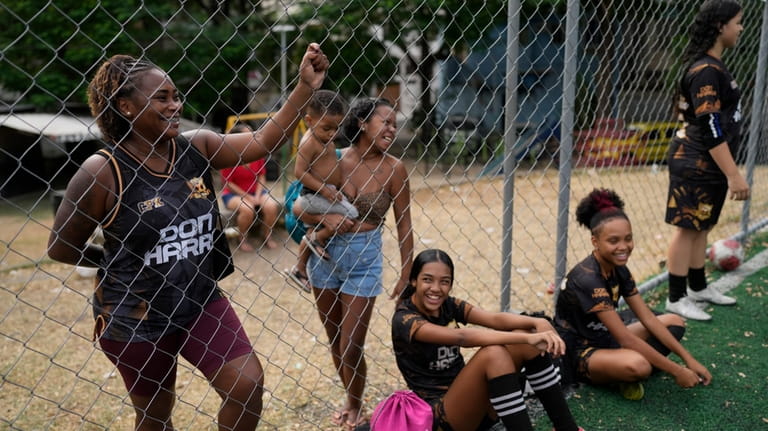 Relatives watch a soccer training session for young women run...