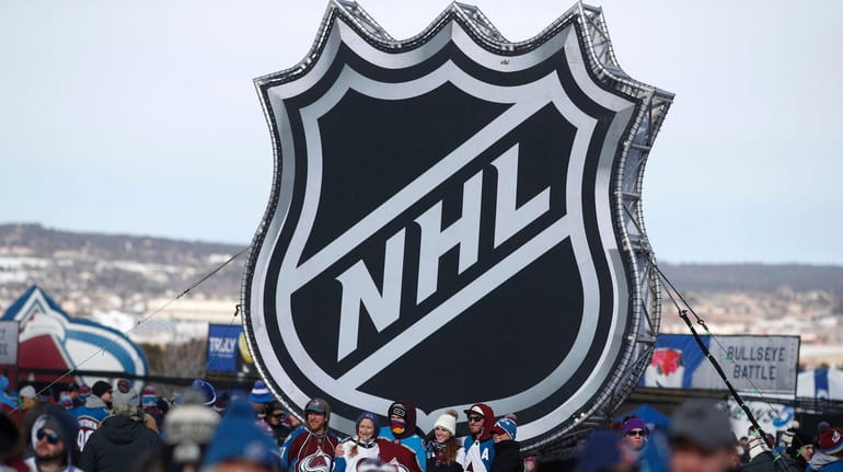 Fans pose below the NHL league logo at a display...