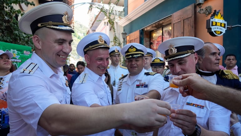Russian crew members toast with a traditional Venezuelan drink during...
