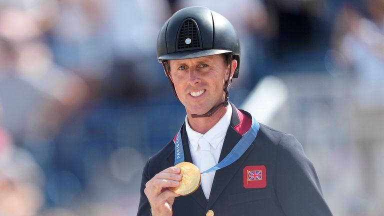 Britain's Ben Maher shows his gold medal after the Equestrian...