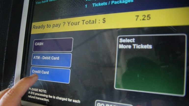 A commuter uses a ticket machine at the LIRR station...