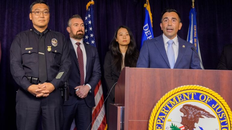 United States Attorney Martin Estrada, at podium, is joined by...