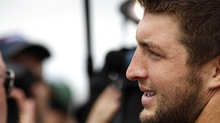 Tim Tebow talks to reporters during the first day of...
