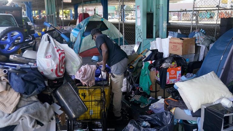 Michael Johnson gathers possessions to take before a homeless encampment...