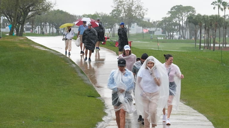 Spectators exit the course as heavy rain delays the final...