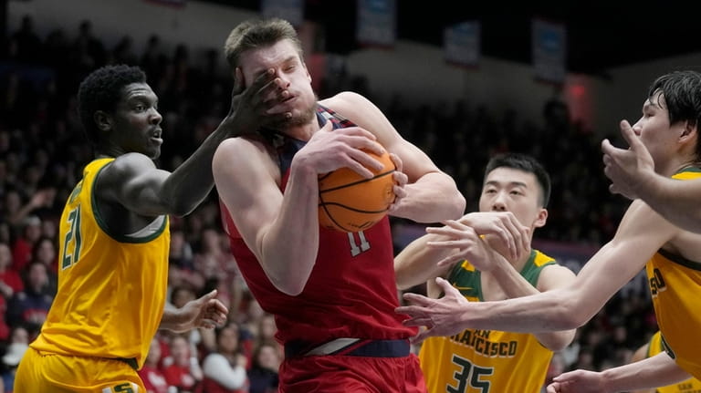 Saint Mary's center Mitchell Saxen, middle, is fouled while driving...