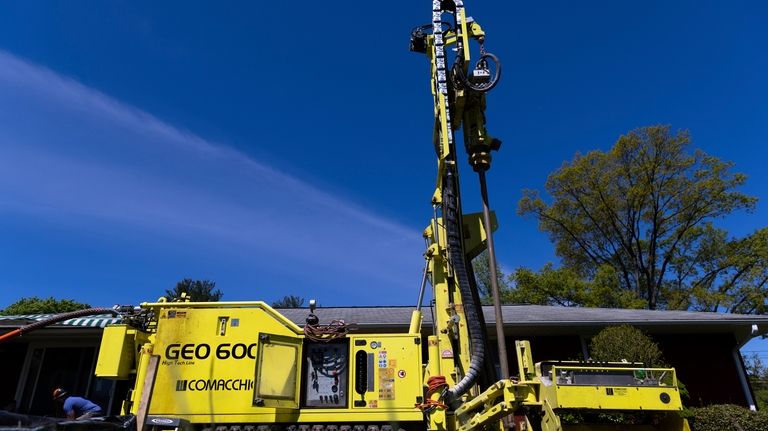 A drill rig sits outside a home during installation of...