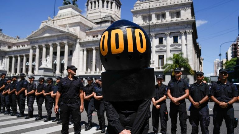 A demonstrator wearing the Spanish word "Hate" stands in front...