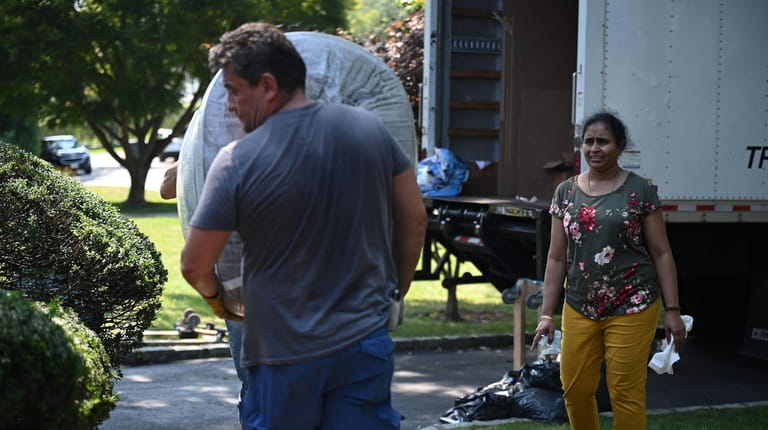 Movers unload the Rasaputras' furnishings at their new home in Smithtown.