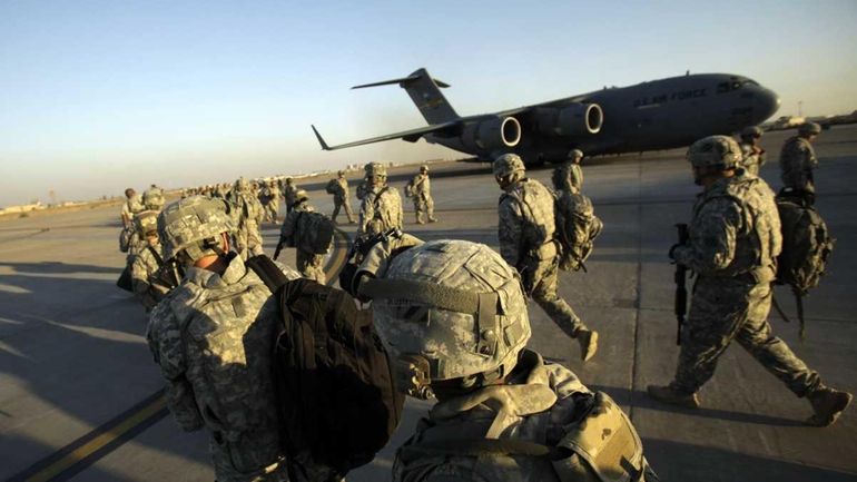 U.S. Army soldiers walk toward a C-17 aircraft in Baghdad...