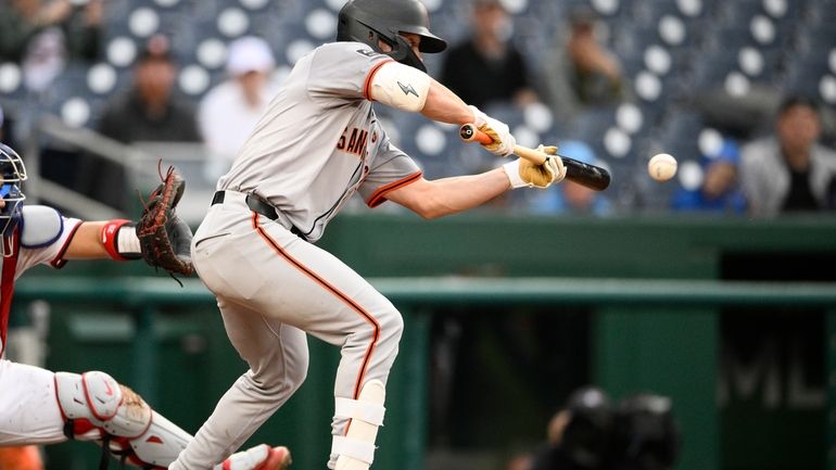 San Francisco Giants' Brett Wisely hits a bunt single that...