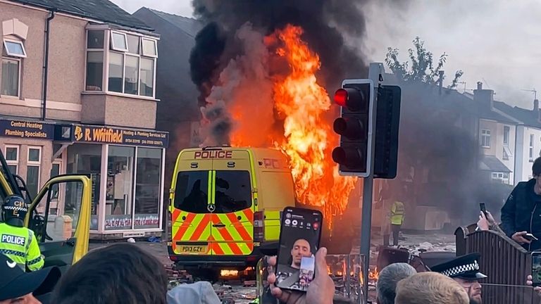 A police van buns as and unruly crowd clashed with...