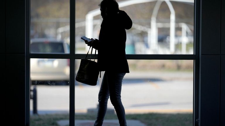 A woman looks at her phone before the start of...