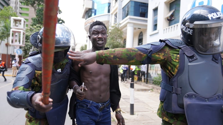 Kenyan riot police arrest a man during a protest over...