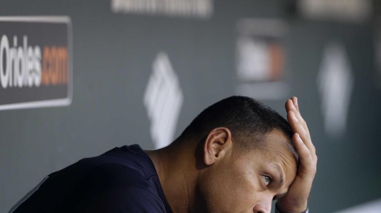 Alex Rodriguez wipes sweat from his brow as he sits...