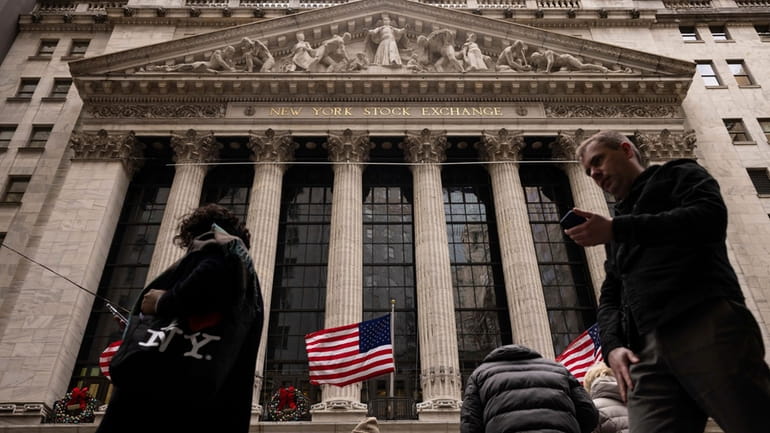 People walk past the New York Stock Exchange, Dec. 11,...