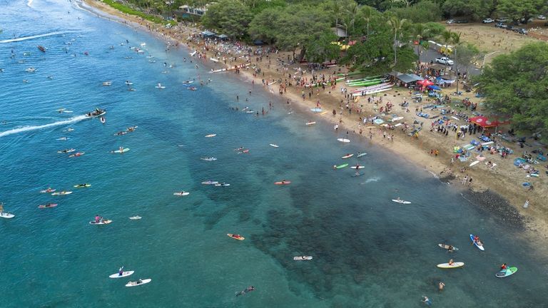 Aerial view of surfers and canoe clubs paddling out at...