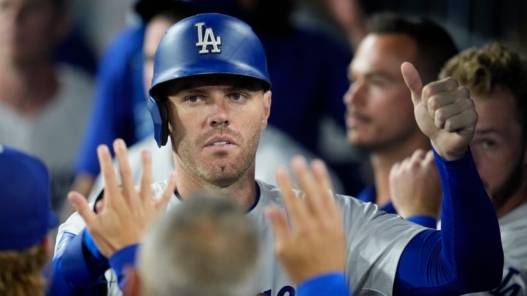 Los Angeles Dodgers' Freddie Freeman is high-fived in the dugout...