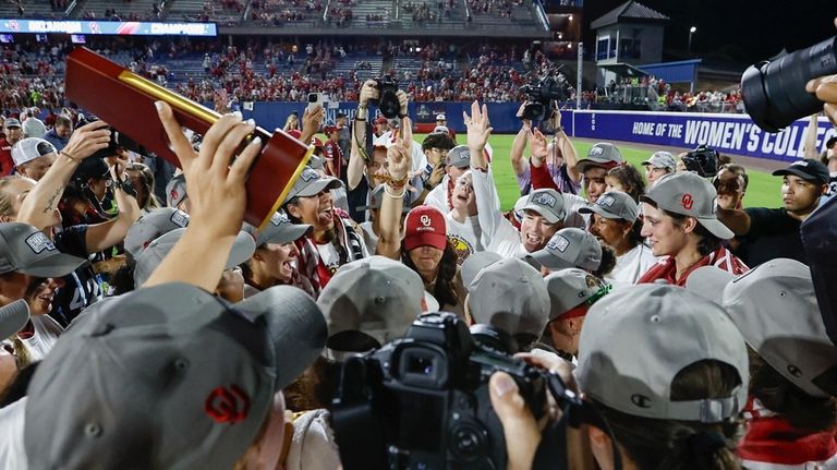 Oklahoma coach Patty Gasso, hand raised, with white sleeve, celebrates...