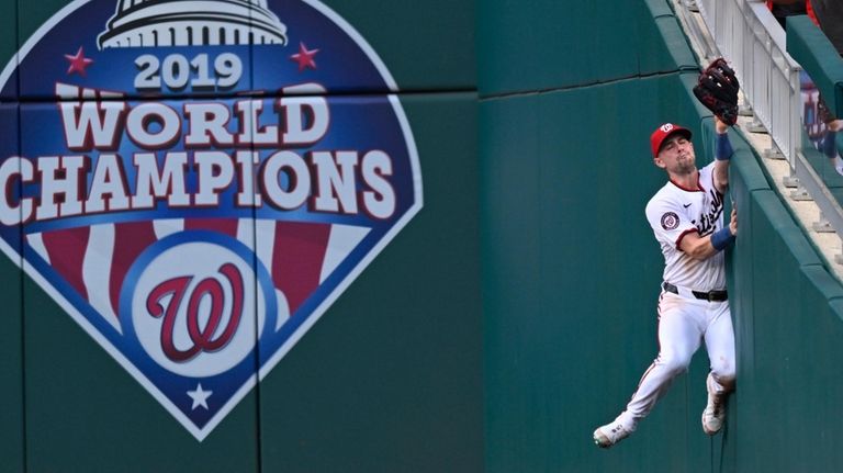 Washington Nationals right fielder Lane Thomas slams into the wall...