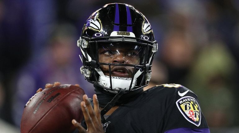 Lamar Jackson of the Baltimore Ravens warms up by throwing...