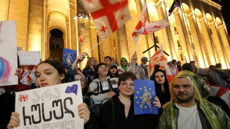 Demonstrators with Georgian national and EU flags, one of them...