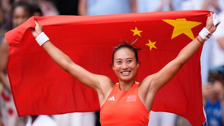 China's Zheng Qinwen holds her national flag after defeating Croatia's...