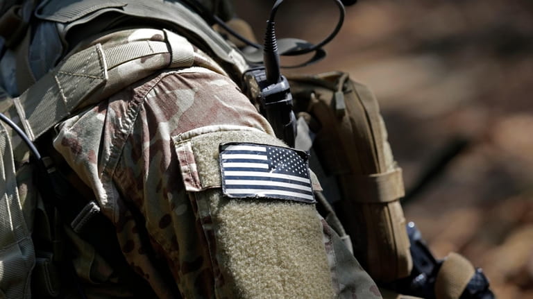 A U.S. flag patch adorns the uniform of a paratrooper,...