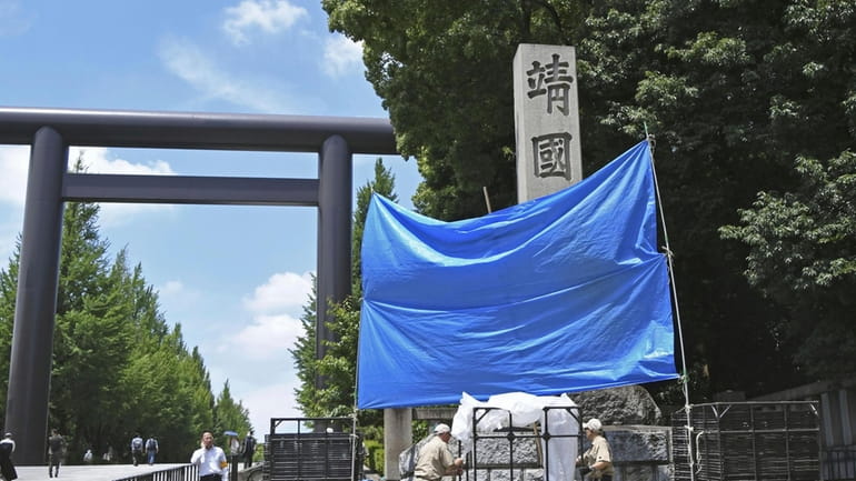 Workers attend to removing a graffiti on Yasukuni Shrine's stone...