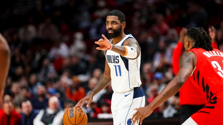 Dallas Mavericks guard Kyrie Irving gestures to teammates during the...
