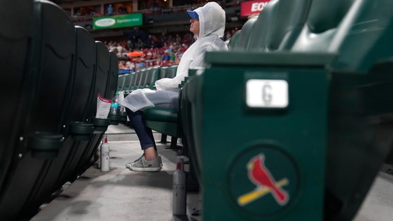 A fan sits in the stands wearing a rain poncho...