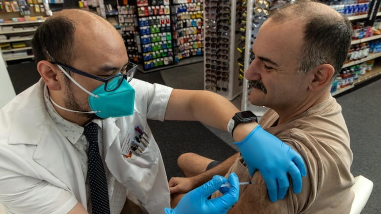 Pharmacist Aaron Sun administers the new COVID-19 vaccine by Pfizer...