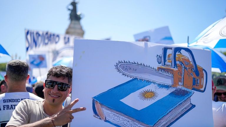 A demonstrator holds a poster showing a chainsaw over the...