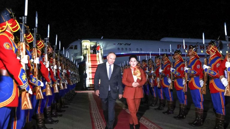 Russian President Vladimir Putin, on red carpet left, walks next...