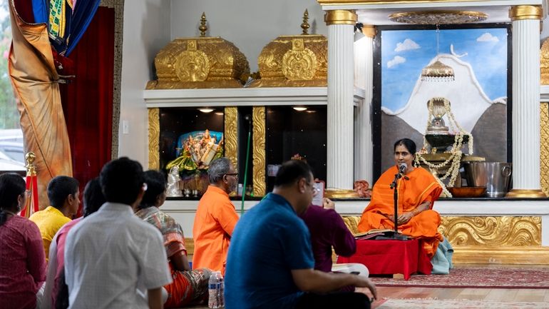 Amma Jyotirmaye, a devotional singer, right, vocalizes while worshippers listen...