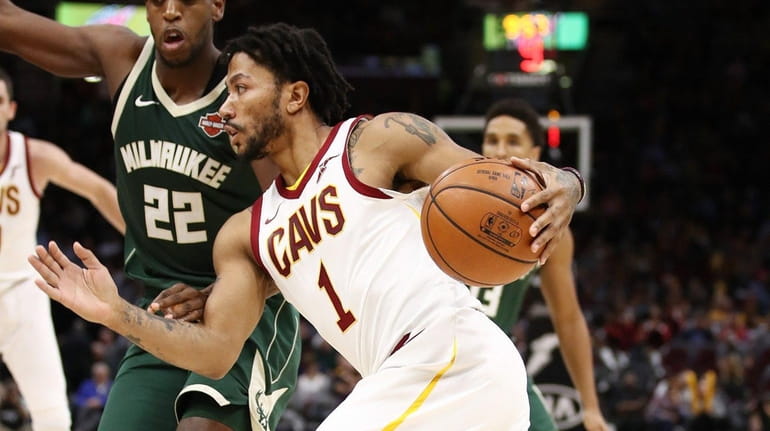 Derrick Rose of the Cleveland Cavaliers drives around Khris Middleton...