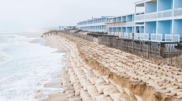 Erosion along an artificial dune made from sandbags in front...