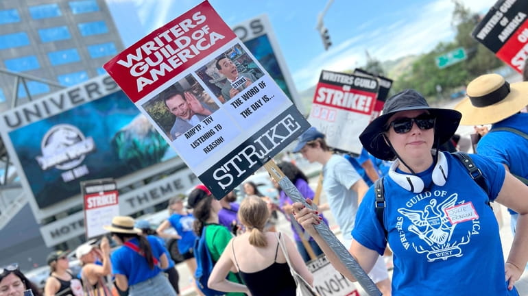 Writer Julie Benson holds a picket sign with an image...