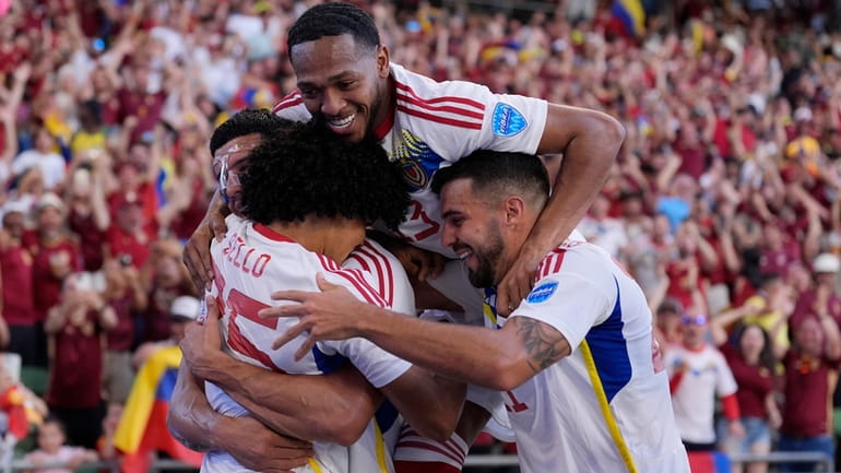 Venezuela's Eduard Bello, left, celebrates with teammates after scoring a...