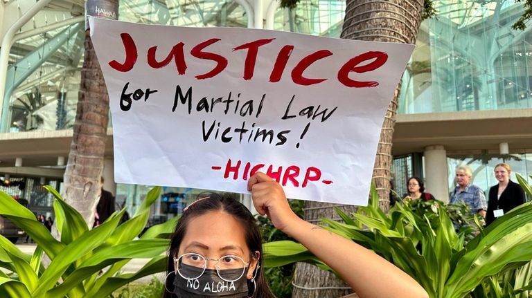 Protester Ia Maranon holds a sign outside the Hawaii Convention...